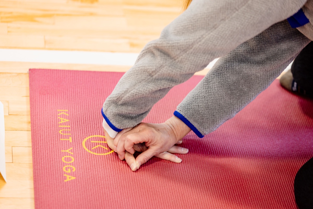 Close view of two hands pressed flat on a yoga mat, working the wrists